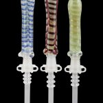 Three colorful glass dab tools with detailed, ornamental handles and clear tips, displayed against a black background.
