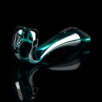 A vibrant teal glass pipe with intricate sculpted details, presented against a stark black background.
