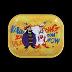 A yellow rolling tray featuring cartoon depictions of Samuel L. Jackson and Pedro Pascal with comic book-style onomatopoeia like ""Kaboom"" and ""Bang."""