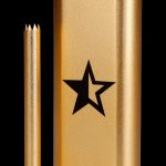 Gold cannabis one-hitter pipe with a star emblem and accompanying cleaning tool.
