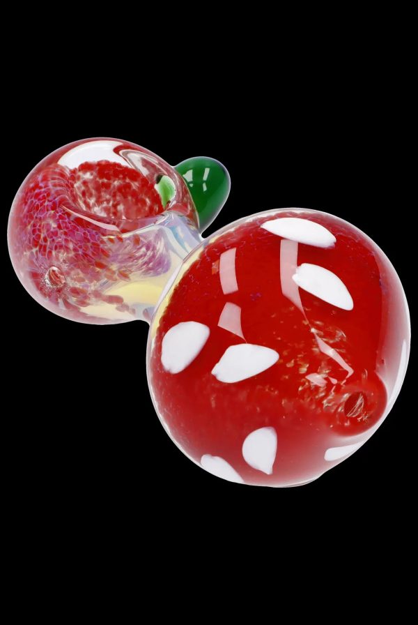 Red and white spotted glass mushroom-shaped cannabis pipe against a black background.