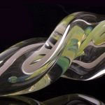 Close-up view of the Green Slyme and Bubble Gum Inside-Out Pipe with Black Marbles, showcasing its swirling glass design.