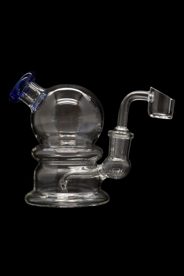 Clear glass dab rig with a spherical body and quartz banger, isolated on a black background.