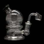 Clear glass dab rig with a spherical chamber and accompanying quartz banger, isolated on a black background.