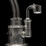 Clear glass dab rig with a quartz banger, isolated on a black background.