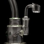 Clear glass dab rig with green accents and a quartz banger.