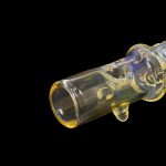 Glass cannabis oil burner pipe with colorful swirls against a black background.