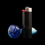 Glass cannabis smoking piece and black lighter isolated on black background.