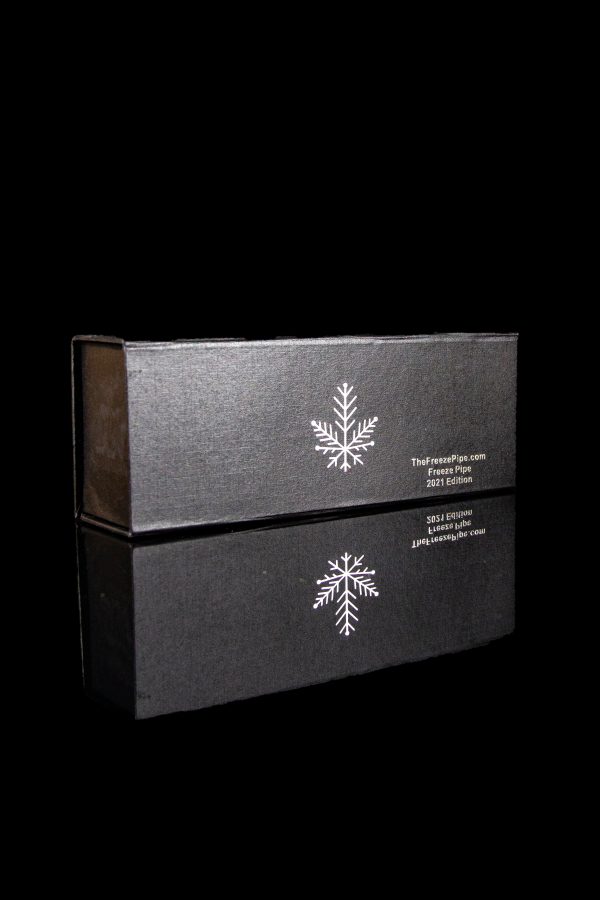 Black box with a snowflake design and cannabis accessory branding, reflected on a dark surface.