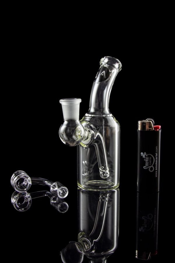 Clear glass water pipe (bong) with loose glass marbles and a lighter reflected on a glossy black surface.