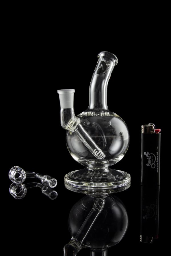 Clear glass water pipe (bubbler) with accompanying glass pieces and lighter, studio shot against a black background.