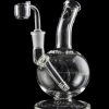 Clear glass dab rig with intricate design and accompanying nail, isolated on a black background.