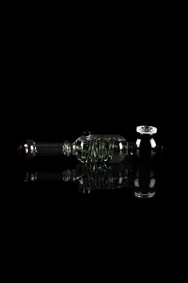 Clear glass rig with intricate bubbler design, reflecting on a dark surface.