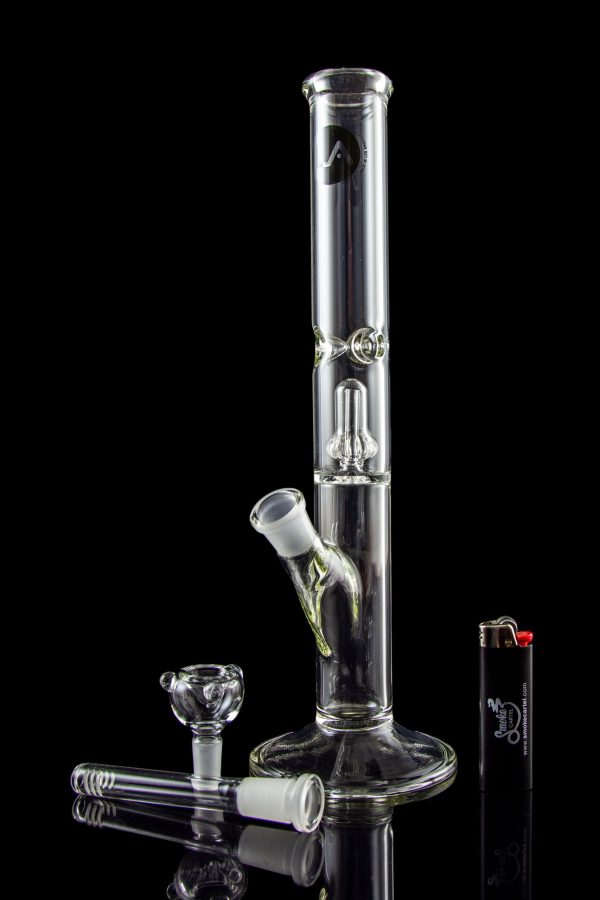 Glass bong with accessories on a reflective surface.