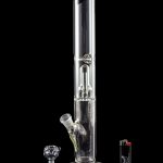 Glass bong with accessories and lighter on black background.