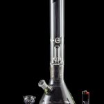 Clear glass bong with various attachments and accessories, reflecting on a black surface.