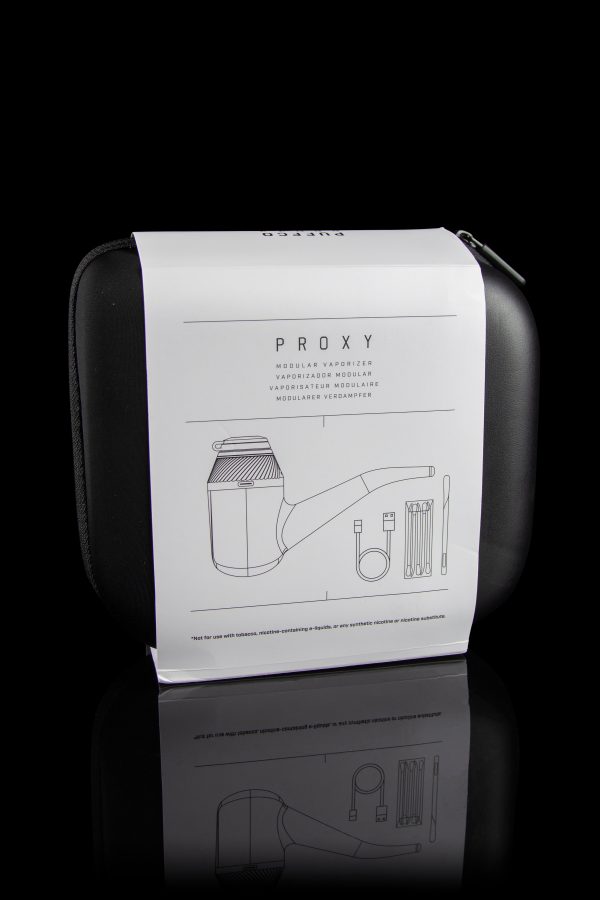 Closed black case for a “PROXY” modular vaporizer with line-drawing diagrams of components and a disclaimer against use with nicotine products, reflected on a glossy surface.