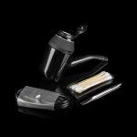 Black cannabis grinder, filter tips, and charging cable on a dark surface.