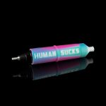 A colorful cannabis oil syringe with “HUMAN SUCKS” printed on the side, reflected on a glossy black surface.