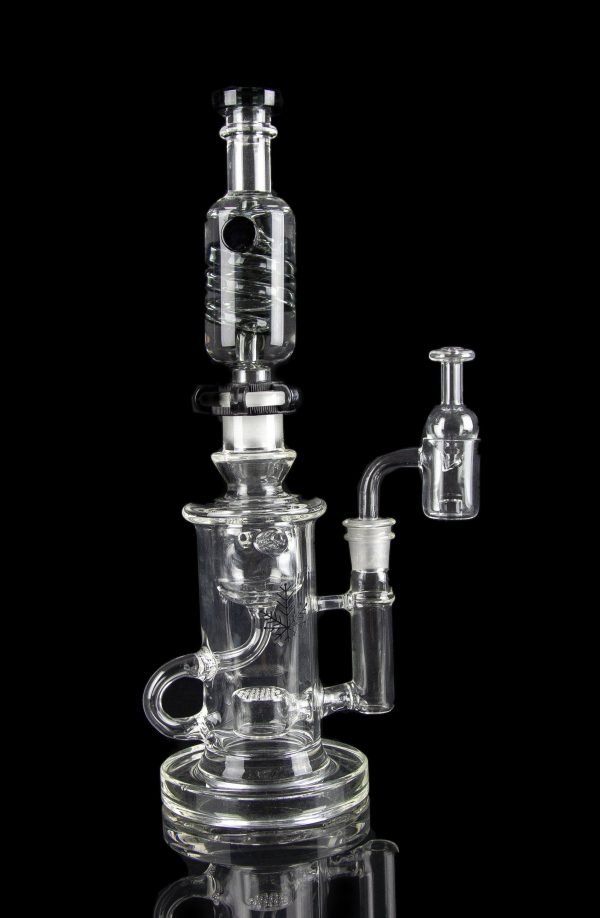 Clear glass water pipe (rig) with multiple chambers and a separate oil dome, isolated on a black background.