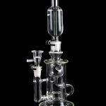 Clear glass water pipe (rig) with multiple chambers and attachments, isolated on a black background.