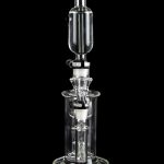 Clear glass dab rig with intricate percolator chambers, isolated on a black background.