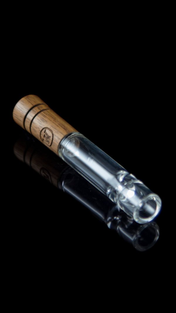 Glass pipe with wooden mouthpiece on a reflective surface.