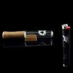 Glass cannabis pipe with wooden mouthpiece and lighter on black background.