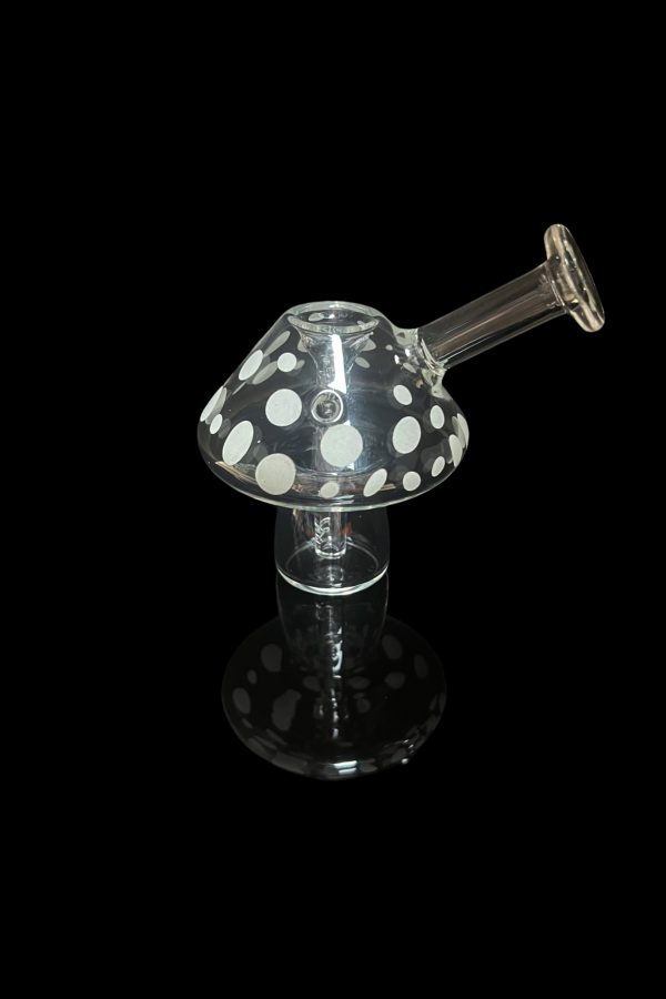 Glass mushroom-shaped dab rig with white polka dots, isolated on black.