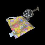 A glass bubbler pipe rests beside a colorful, patterned draw string bag featuring psychedelic floral and mushroom designs.