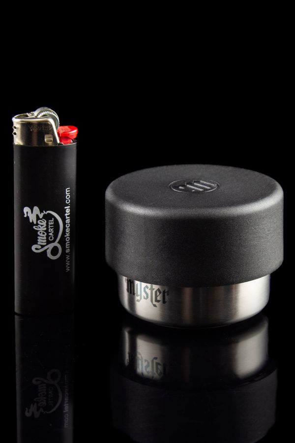 Black cannabis storage jar and lighter with branding for Smoke Cartel, reflecting on a glossy surface.