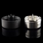 Silver cannabis smoking bowl with a spiked interior and removable screen, reflected on a dark surface.