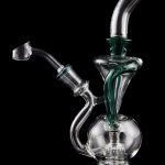 Clear glass water pipe (rig) with green accents, studio shot on black reflective surface.