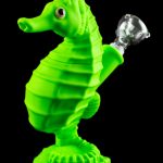 Green glass seahorse-shaped water pipe with a clear glass bowl, studio shot on a reflective surface.