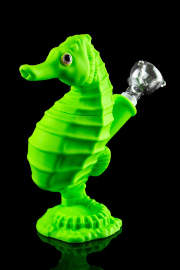 Green glass seahorse-shaped water pipe with a clear glass bowl, studio shot on a reflective surface.