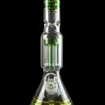 Glass water pipe (bong) with intricate percolators and green accents, isolated on a black background.