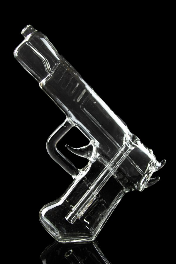 Clear glass pipe shaped like a handgun, reflecting on a dark surface.