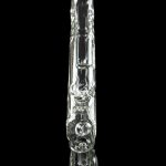Clear glass bubbler with intricate sculpted design, reflected on a black surface.