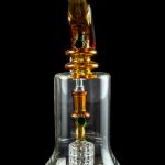 A detailed glass rig with orange and clear glass components, featuring a honeycomb perc diffuser and a spherical mouthpiece, set against a black background.