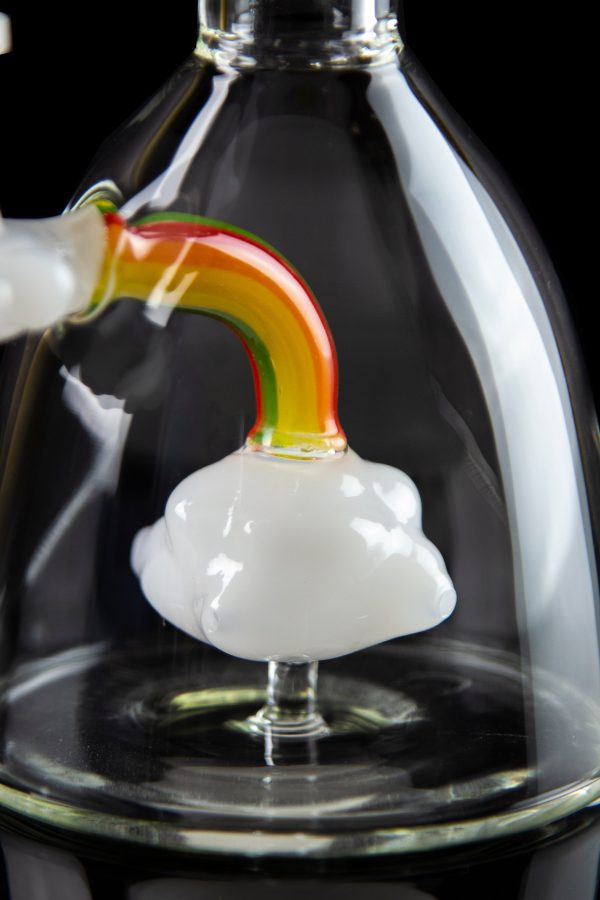 A close-up of a glass cannabis oil rig with a white and colorful mouthpiece, set against a dark background.