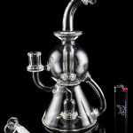 Clear glass water pipe (bong) with multiple chambers and a glass bowl, displayed on a black background.