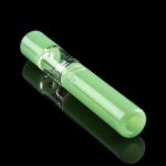 Green glass chillum with a visible chamber, reflecting on a black surface.