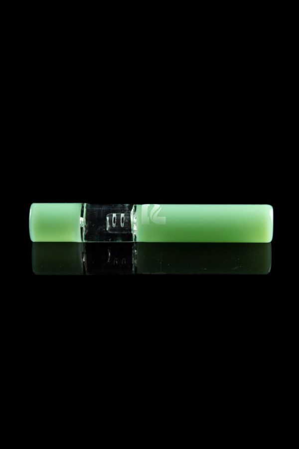 Glowing green cannabis oil vape pen with a metallic center section, displayed on a reflective black surface.