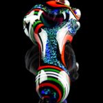 Colorful glass pipe with swirling red, white, and green patterns against a black background.
