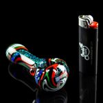 Colorful glass pipe and lighter on a black reflective surface.