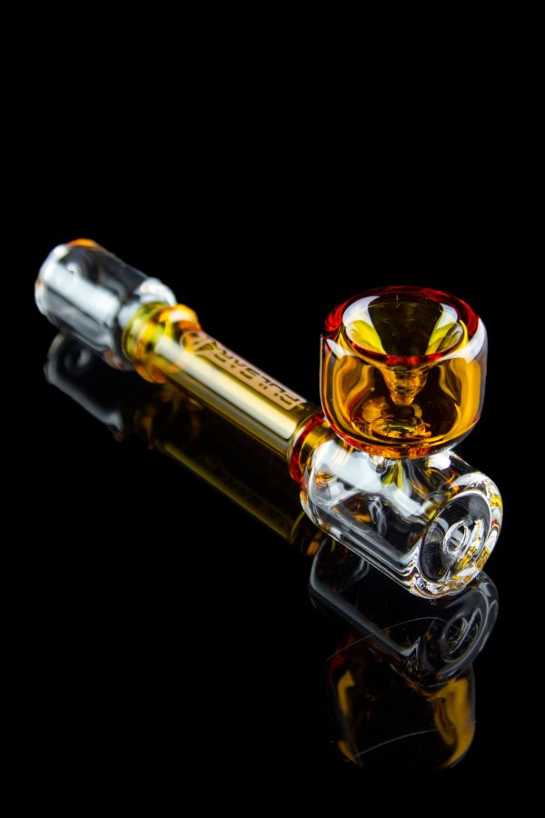 A vibrant orange and clear glass cannabis pipe with intricate detailing, displayed against a black reflective surface.