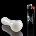 White glass pipe and lighter with “Smoke Cartel” branding, reflected on a glossy black surface.