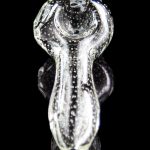 Clear glass bubbler pipe with speckled pattern, reflecting on a dark surface.