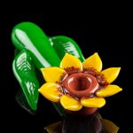 Glass sunflower pipe with green leaf base, studio shot on black background.