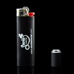 Black lighter with "Smoke Cartel" branding and disassembled components reflecting on a dark surface.